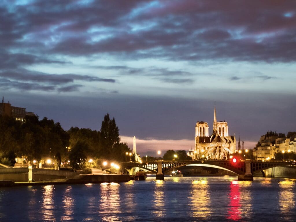 Paris view from the River Seine of Île de la Cité and rear of lit up Notre-Dame Cathedral at night