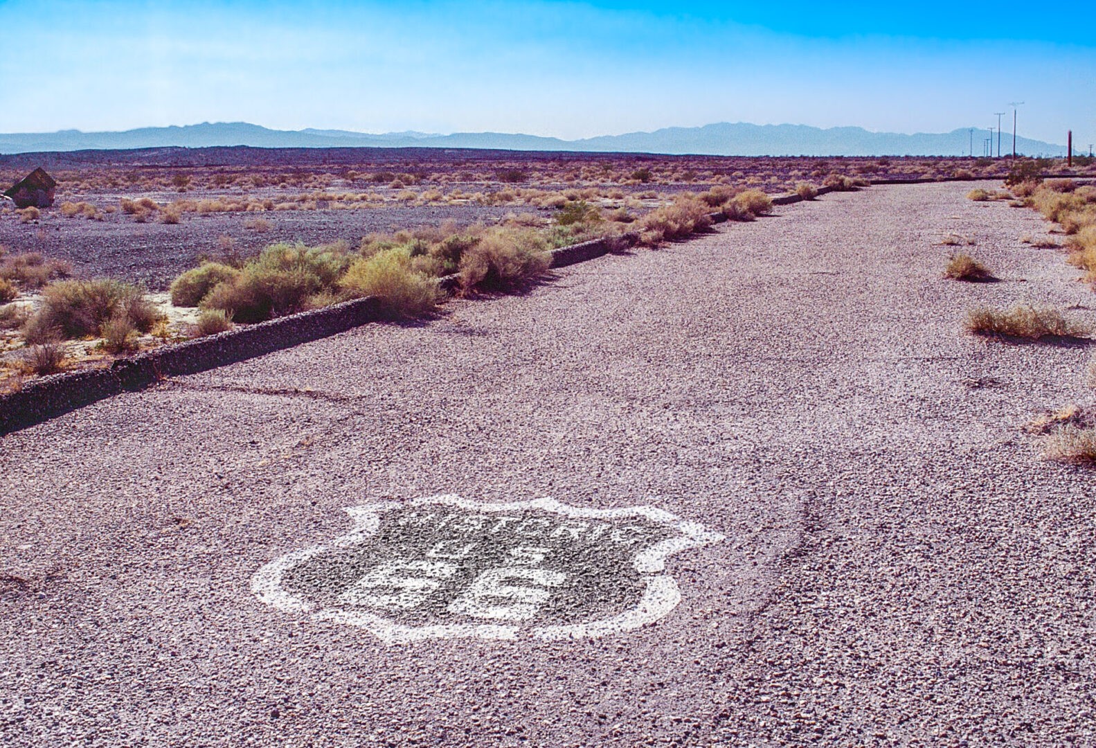 Original Historic Route 66 roadway in the Mojave Desert with Route 66 shield painted on the road