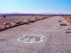 Original Historic Route 66 roadway in the Mojave Desert with Route 66 shield painted on the road