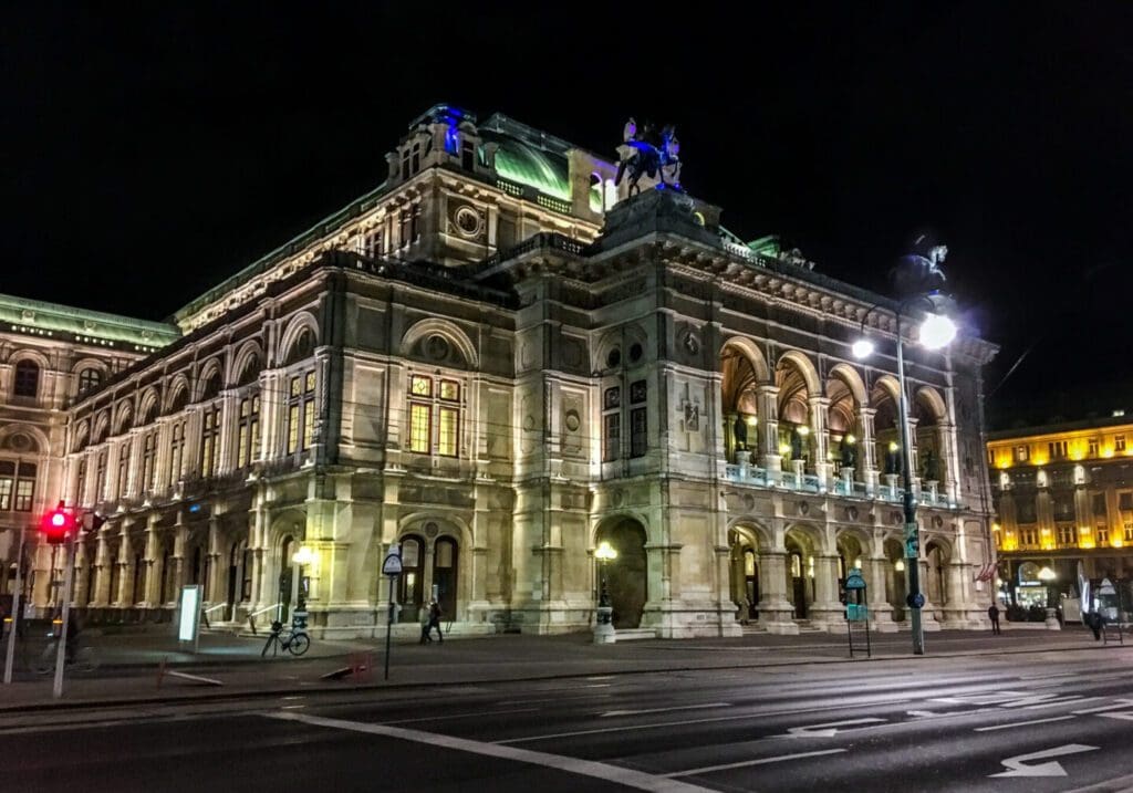 Dramatic night time photo of the Vienna Operahouse, lit up dramatically with deserted streets