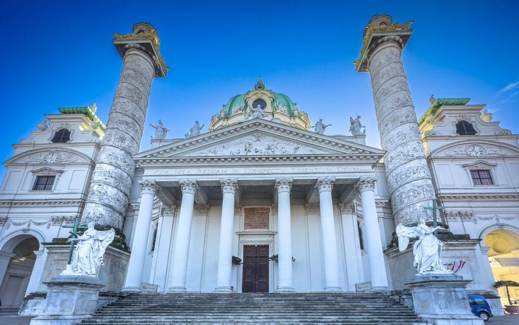 Photo of 18th century Baroque church with intricate detailed dome, dedicated to St. Charles Borromeo, with a Greek temple portico flanked by two copies of Trajan's columns