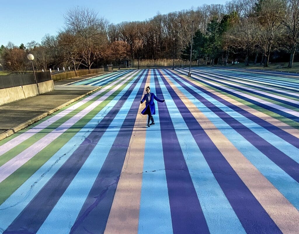 Parking lot with coloured stripes painted on the ground covering more than 43,000 square feet (4m2) in blue, pink and yellow hues as the trees in the background are undergoing their change of colours in early Fall.