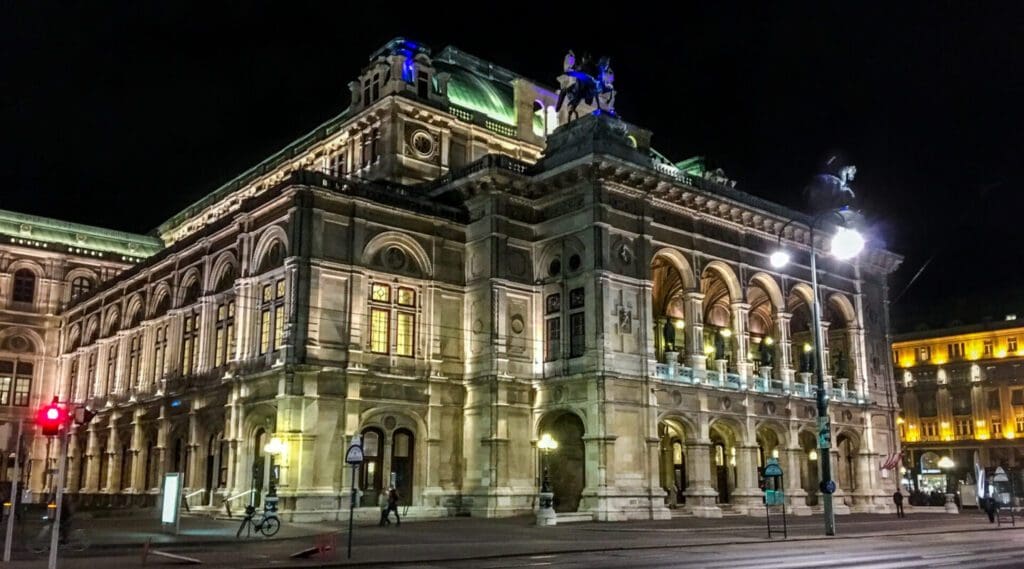 Nighttime photo of the Vienna State Opera House, with the Istrian stone of the Neo-Renaissance arched style bathed in light