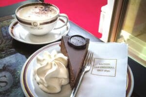 Slice of the original Sacher torte with a cappuccino as served in the cafe of the Sacher Hotel in Vienna Austria