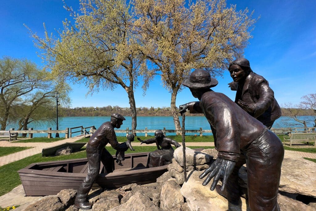 Bronze sculptures of five figures, three passengers, stationmaster, and fictional heroine represent the Freedom Crossing Monument to honor Underground Railroad 