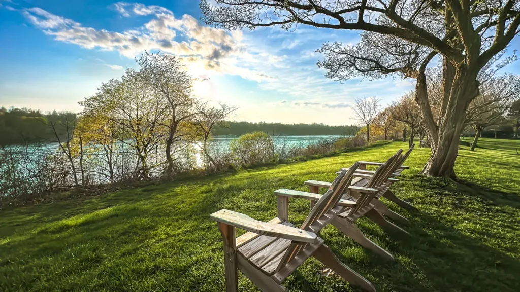 A couple of wooden lawn chairs sitting on top of grass.