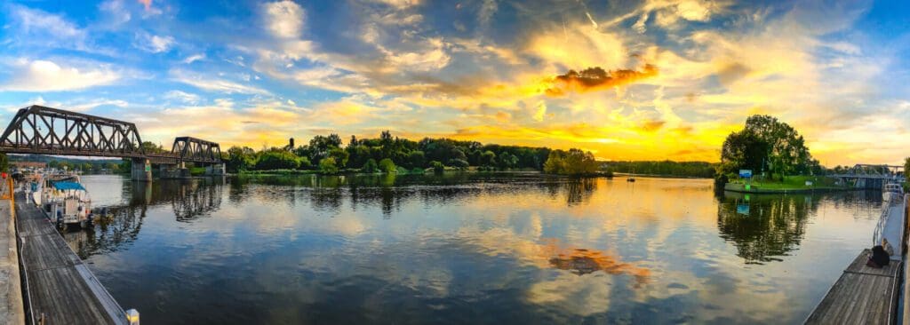 Panoramic view of a late golden summer sunset as the rivers Mohawk and Hudson Rivers meet. An iron wrought bridge on one end the first modern lock on the other end.