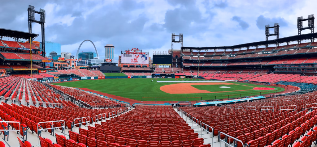 A baseball stadium with red seats and a green field.