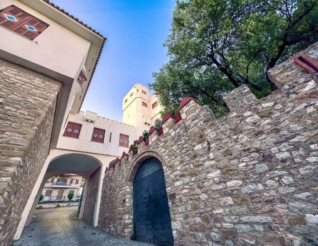 Medieval street and walls with a the white tower of Botsaris in the background in the old town of Nafpaktos.