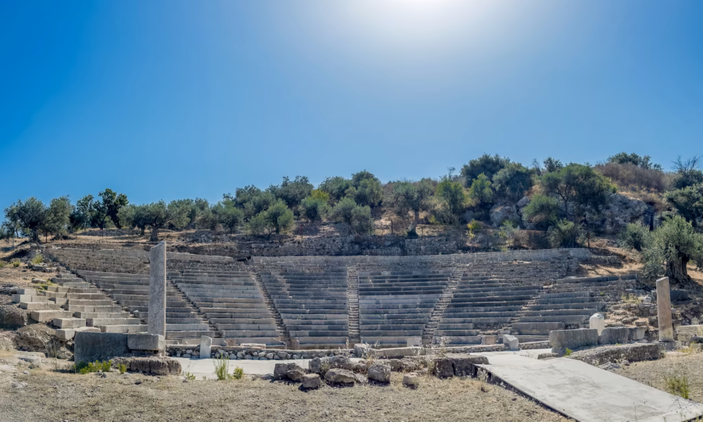A large stone structure in the middle of an empty field is the Little Theater of Ancient Epidauros