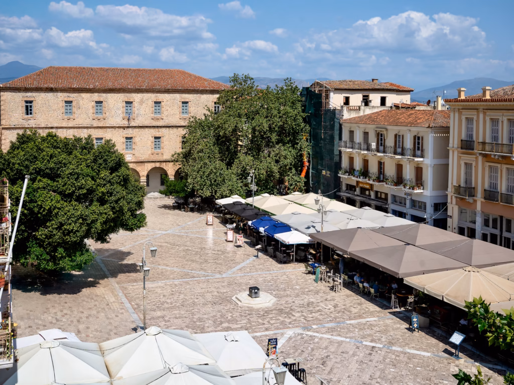 A square with many tables and umbrellas in it