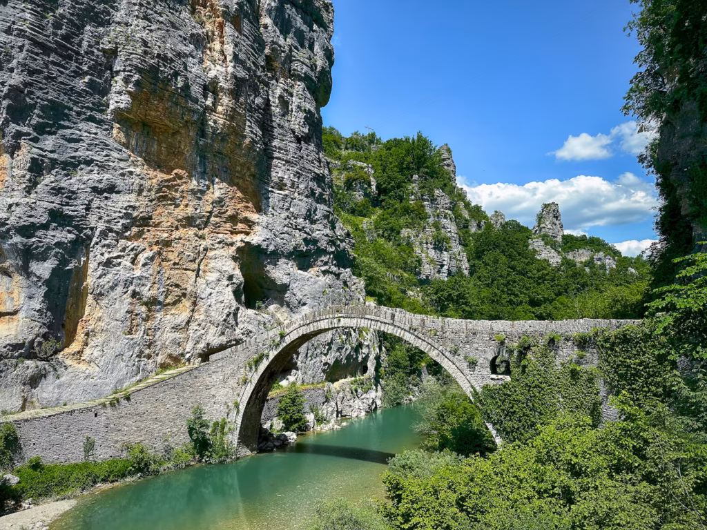 A bridge over water near some rocks and trees.
