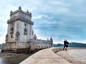A man standing on the side of a road near a castle.