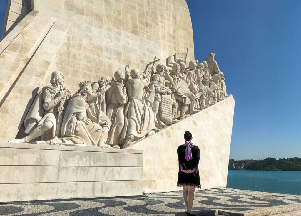 Admiring the iconic Padrão dos Descobrimentos monument in Lisbon, Portugal, with detailed stone sculptures depicting historical explorers, set against a clear blue sky and riverfront view. Perfect stop for a 3 days in Lisbon Portugal itinerary or Lisbon itinerary highlights."





