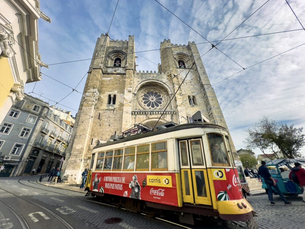 The Lisbon Cathedral facade with the iconic number 28 yellow tram passing by