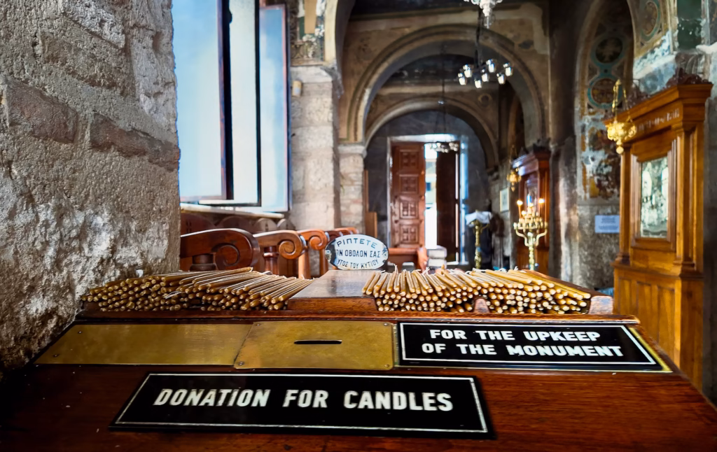 Interior photo of a Greek Orthodox church with the candle offertory in the foreground. Photo by Paul Kostadimas © spotlightsojourns.com