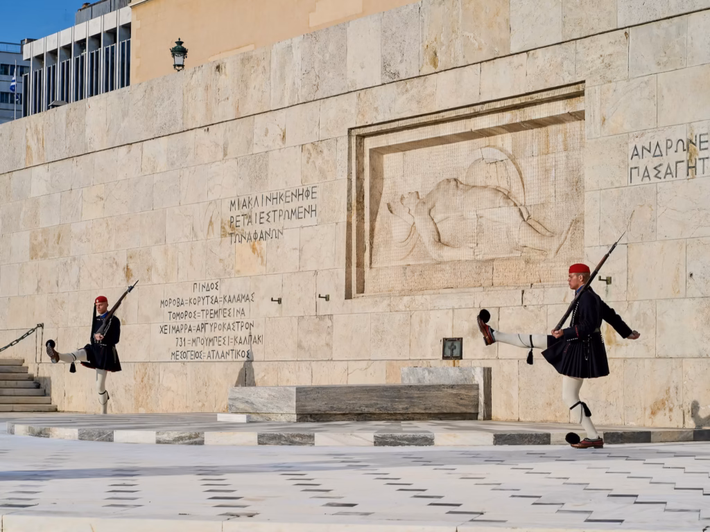 Two Evzones in black and red uniforms are guarding the Tomb of the unknown soldier in Syntagma Square in Athens Greece. Photo by Paul Kostadimas © SpotlightSojourns.com