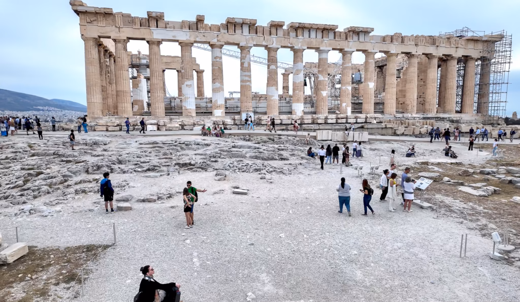 Sitting on a rock of the Acropolis enjoying a view of the Parthenon. Plan your trip to the Parthenon ahead of your trip. High demand in season can sell out time entries to the Acropolis.