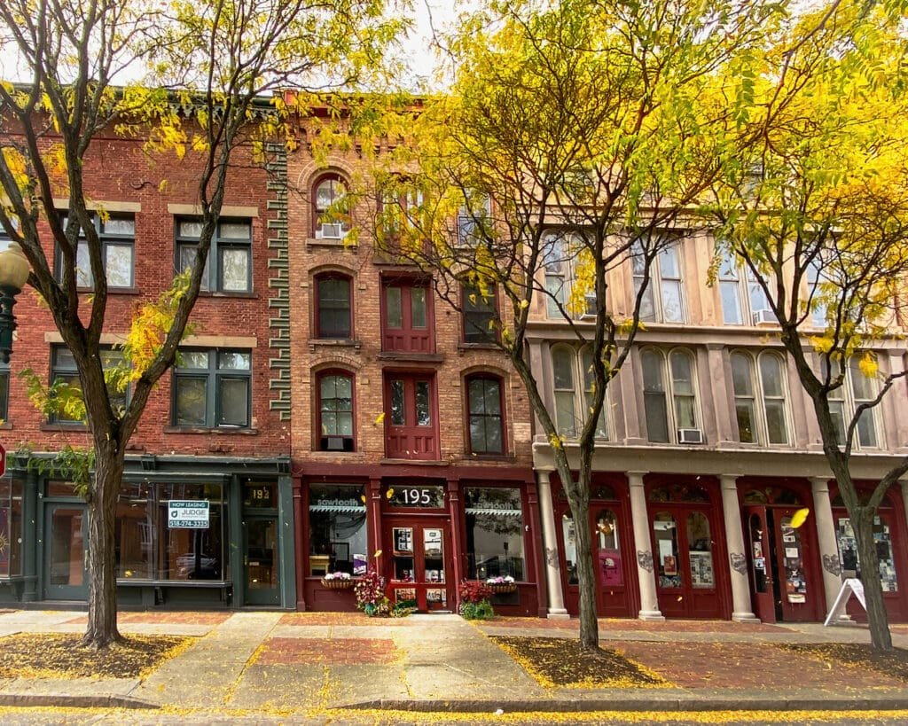 The Erie canalway has wonderful historic cities along every mile, like Troy, New York, with its historic downtown buildings, pictured here during fall with the trees turning leaves.