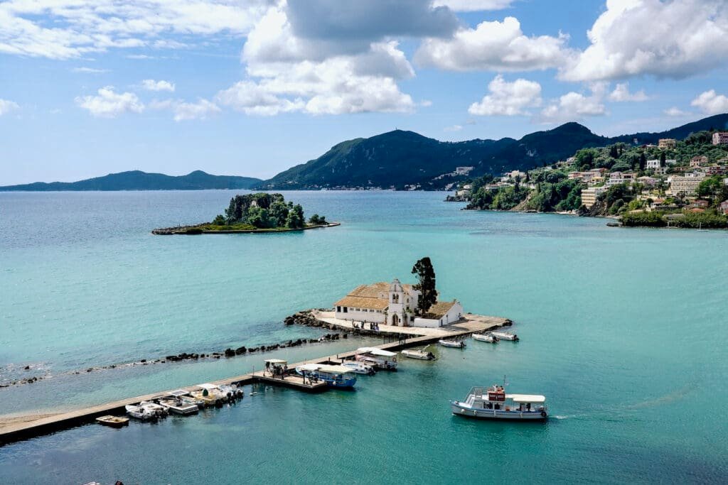 Small boat pulling into a small port next to Vlacherna Monastery with, the legendary Mouse Island of Pontikonisi in the background, in Corfu, Greece