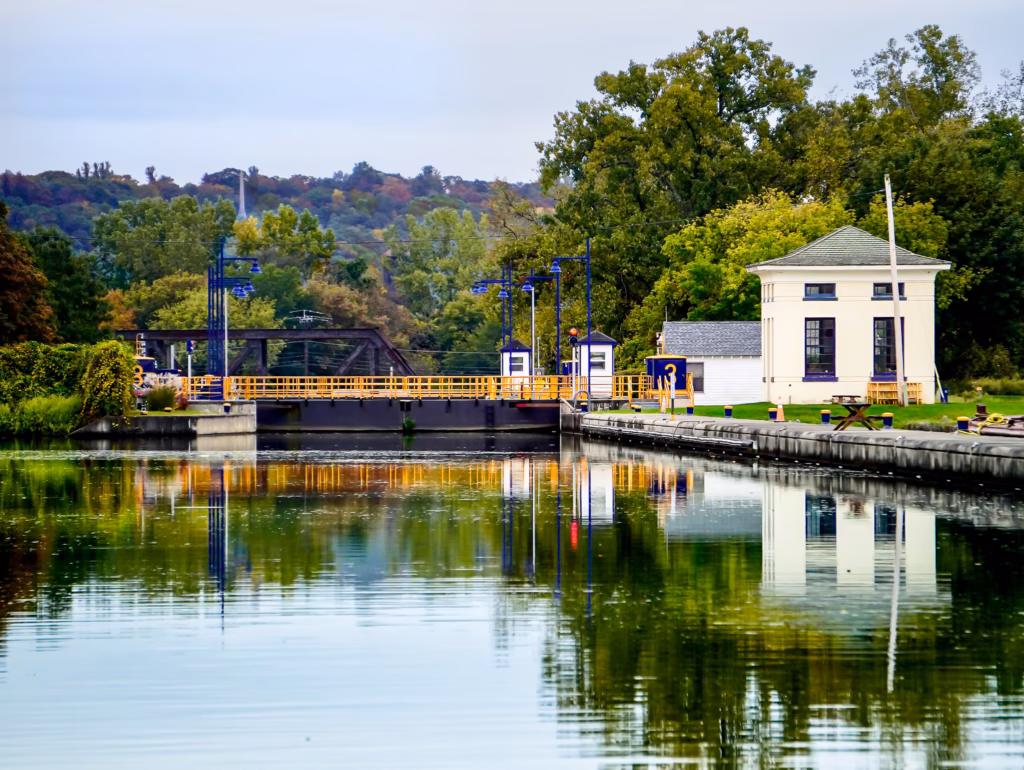 A dock with houses and trees in the background. Lock E3 on the Erie canalway