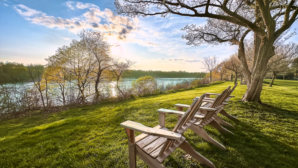 A couple of wooden lawn chairs sitting on top of grass.