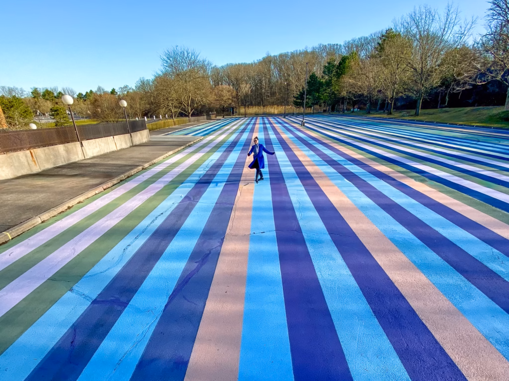 Parking lot with coloured stripes painted on the ground covering more than 43,000 square feet (4m2) in blue, pink and yellow hues as the trees in the background are undergoing their change of colours in early Fall. New York's hidden gem