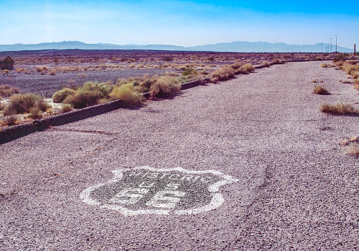 Original Historic Route 66 roadway in the Mojave Desert with Route 66 shield painted on the road